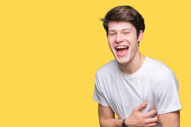 Casual beyaz t-shirt üzerinde izole giyen genç yakışıklı adam arka plan gülen ve komik deli şaka çünkü yüksek sesle zor gülüyor. Mutlu ifade.