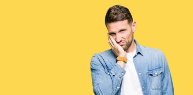 Yakışıklı adam mavi gözleri ve denim ceket düşünme seyir giyen sakal yorgun ve sıkılmış çapraz silah depresyon sorunları ile.