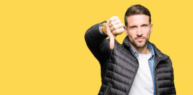 Yakışıklı adam mutsuz ve kızgın ret gösterilen ve başparmak aşağı hareketi ile negatif seyir kış palto giyiyor. Kötü ifade.