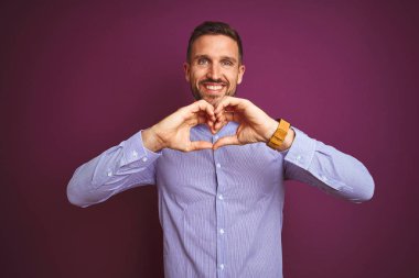 Mor izole arka plan üzerinde zarif gömlek giyen genç iş adamı elleriyle kalp sembolü ve şekil gösteren aşk gülümseyerek. Romantik kavram.