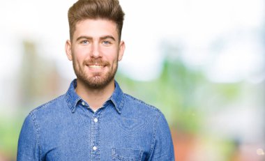 Yüzünde mutlu ve güzel bir gülümseme ile rahat kot gömlek giymiş genç yakışıklı sarışın adam. Şanslı kişi.