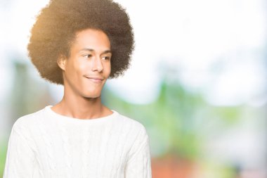 Afrikalı-Amerikalı genç afro saçlı kış kazak uzak tarafına gülümseme ile yüzünde, doğal ifade arıyorum giyiyor. Kendine güvenen gülüyor.