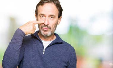 Orta yaş yakışıklı adam kazak giyiyor yüz ve burun, neşeli gülümseyerek el parmak ile işaret