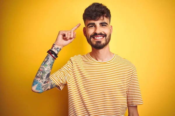 Mladý Muž Tetováním Proužkované Košili Stojící Nad Izolovaným Žlutým Pozadím — Stock fotografie