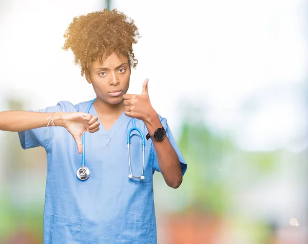 Young african american doctor woman over isolated background Doing thumbs up and down, disagreement and agreement expression. Crazy conflict