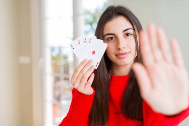 Güzel genç kadın ciddi ve kendinden emin ifade, savunma jesti ile durdurmak işareti yapıyor açık el ile poker oynarken kumar