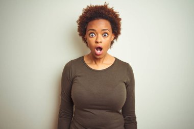 Izole arka plan üzerinde afro saçlı genç güzel afro-Amerikan kadın korkmuş ve sürpriz ifade, korku ve heyecanlı yüz ile şok.