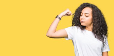 Rahat beyaz t-shirt giyen kıvırcık saçlı Genç güzel kız kol kası gösteren güçlü kişi, emin ve güç gurur