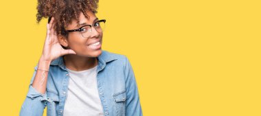 Gözlüklü bir işitme söylenti ya da dedikodu için dinleme kulak üzerinde el ile gülümseyen izole arka plan üzerinde güzel genç Afro-Amerikan kadın. Sağırlık kavramı.