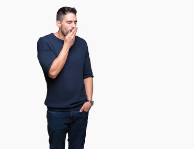 Genç yakışıklı adam kazak giyiyor izole arka plan üzerinde el ile ağız kapsayan yorgun esneme sıkılmış. Restless ve uyku hali.