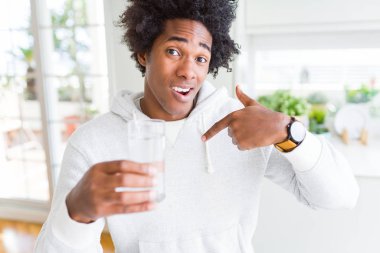 Afro-Amerikan adam sürpriz yüzü kendini işaret eden evde bir bardak su içme