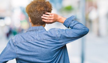 Denim ceket geriye düşünme hakkında şüphe el ile kafasına takmış afro saçlı Genç yakışıklı adam