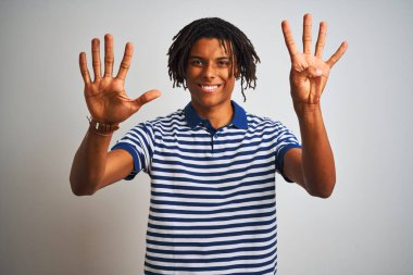 Çizgili mavi polo giyen dreadlocks giyen Afro adam izole beyaz arka plan üzerinde duran gösteren ve emin ve mutlu gülümserken parmakları sayısı dokuz işaret.