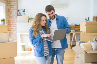 Genç çift araba etrafında bir odada duran bilgisayar dizüstü bilgisayar kullanarak