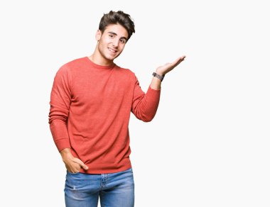 Genç yakışıklı adam neşeli sunulması ve kameraya bakarak avucunun ile işaret gülümseyen izole arka plan üzerinde.