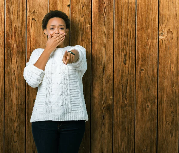 Güzel genç Afro-Amerikan kadın giyiyor kazak izole üzerinde arka plan sizin parmak el kamerasıyla ağzına, utanç ifadesi işaret eden gülme