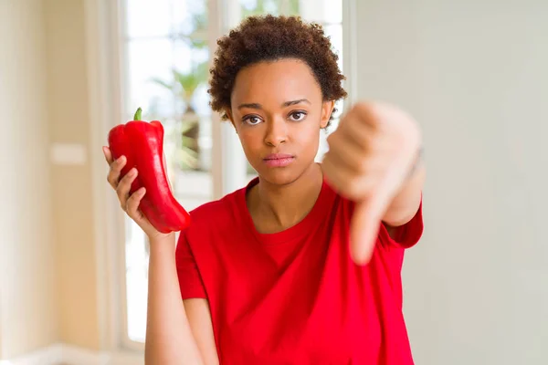 怒った顔で新鮮な赤コショウを持つ若いアフリカ系アメリカ人女性 親指を下にして嫌いを示す否定的なサイン 拒絶概念 — ストック写真