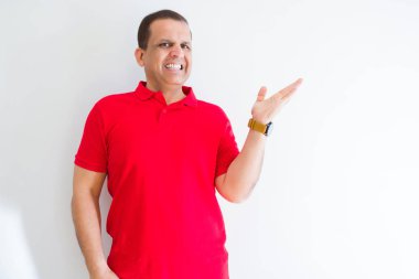 Beyaz duvar üzerinde kırmızı t-shirt giyen orta yaşlı adam neşeli sunan gülümseyerek ve kameraya bakarak avuç içi ile işaret.