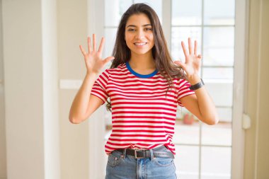 Gösterilen ve parmakları ile işaret rahat t-shirt giyen genç güzel kadın numara 9 kendinden emin ve mutlu gülümseyerek süre.