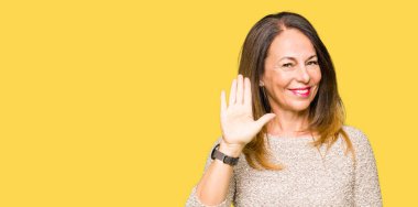 Moda kazak Waiving selam söyleyerek mutlu ve gülümseyerek giyen güzel orta yaş kadın, dostça karşılama jest