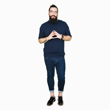 Genç hipster adam uzun saçlı ve gözlüklü eller birlikte sakal ve parmakları ile rahat ve neşeli gülümseyen geçti. Başarı ve iyimser