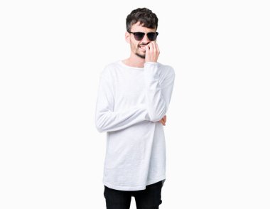 Genç yakışıklı adam stresli ve gergin ile izole arka plan üzerinde güneş gözlüğü takıyor tırnak ısırma dudaklarından eller. Anksiyete sorunu.