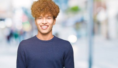 Yüzünde mutlu ve serin bir gülümseme ile afro saçlı genç yakışıklı adam. Şanslı kişi.