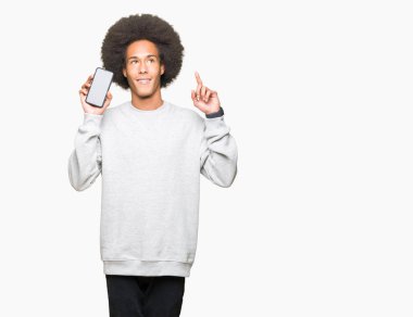 Bir fikir ya da soru işaret parmağı gülen yüz, bir numara ile akıllı telefon ekranını göstermeyi afro saçlı Genç Afrikalı Amerikalı adam şaşırttı