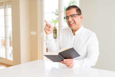 Orta yaş adam evde gözlük takan bir kitap okuma çok mutlu yan el ve parmak ile işaret