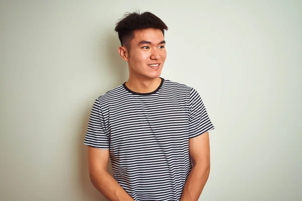 孤立した白い背景の上に立つストライプのTシャツを着たアジアの若い中国人男性は 笑顔で横に向かって 自然な表情 自信を持って笑う — ストック写真