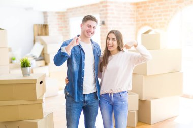 Güzel genç çift yüzünde gülümseme ile emin görünümlü yeni bir eve hareket, parmakları gururlu ve mutlu kendini işaret.