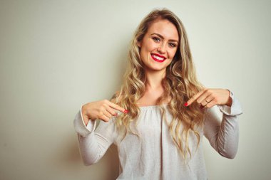 Genç güzel kadın beyaz izole arka plan üzerinde duran yüzünde gülümseme ile emin görünümlü, parmakları gururlu ve mutlu kendini işaret.