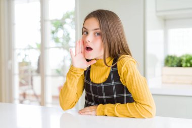 Genç güzel sarışın çocuk kız ağız üzerinde evde rahat sarı kazak giyen gizli söylenti söylüyorum, kötü niyetli konuşma konuşma fısıldıyor