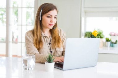 Güzel genç operatör kadın dizüstü bilgisayar ile çalışan ve akıllı yüz ciddi düşünme kendinden emin bir ifade ile headseat giyiyor