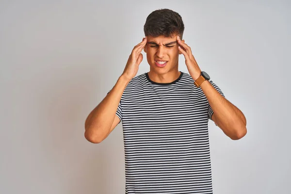 ネイビーのストライプTシャツを着た若いインド人男性は ストレスのために頭の痛みに頭を抱えて孤立した白い背景の上に立っています 苦しむ片頭痛 — ストック写真