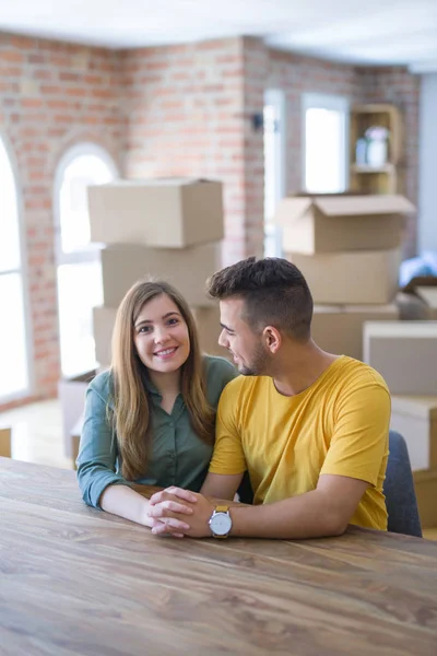 Joven hermosa pareja sentada en la mesa en casa, abrazándose — Foto de Stock