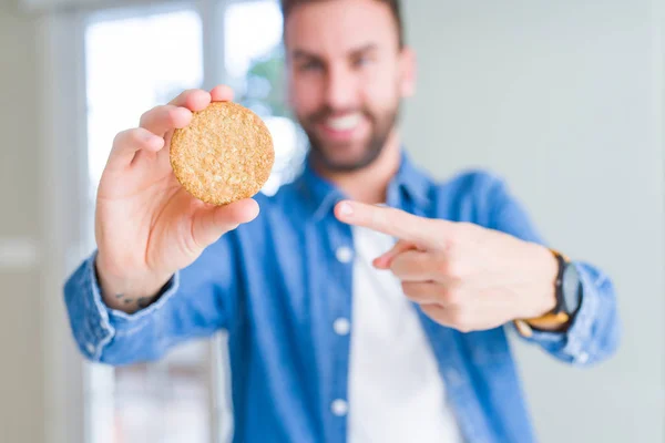 健康的な全粒ビスケットを食べるハンサムな男は 手と指で指し示す非常に幸せ — ストック写真