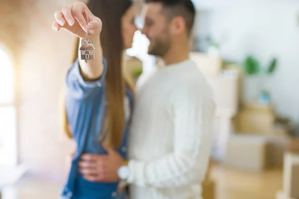 若いカップルは 新しいアパートの鍵を示す愛で抱きしめて新しい家に引っ越して とても幸せな笑顔 — ストック写真