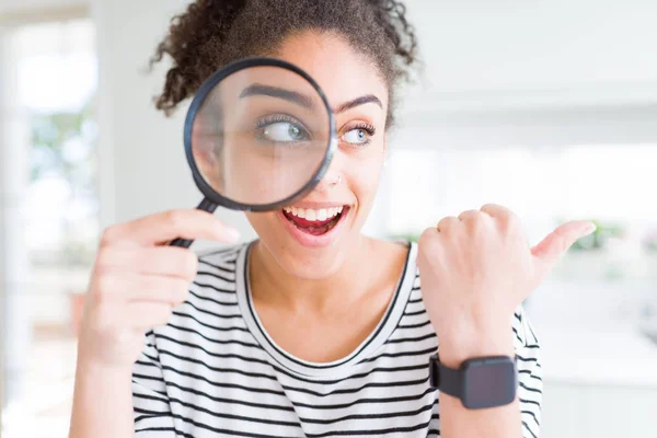 Joven Mujer Afroamericana Mirando Través Lupa Apuntando Mostrando Con Pulgar — Foto de Stock