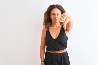 Izole beyaz arka plan üzerinde duran siyah rahat elbise giyen orta yaş kadın mutsuz ve kızgın gösteren reddi gösteren ve aşağı jest başparmak ile negatif. Kötü ifade.