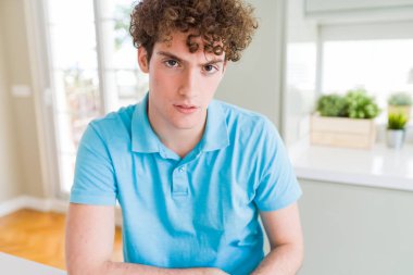 Yüz çapraz kolları olan ev şüpheci ve sinir, onaylamayan ifade rahat mavi t-shirt giyen genç yakışıklı adam. Negatif kişi.