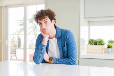 Evde düşünme seyir yorgun ve çapraz kolları olan depresyon sorunları ile sıkılmış rahat denim ceket giyen genç yakışıklı adam.