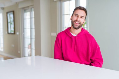 Evde rahat sweatshirt giyen ve olumlu gülümseyen yakışıklı adam