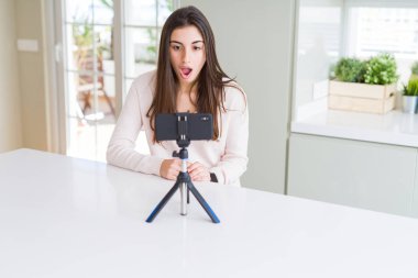 Akıllı telefon web kamerası ile selfie videosu kaydeden güzel genç kadın korku ve sürpriz ifade, korku ve heyecanlı yüz ile şok.