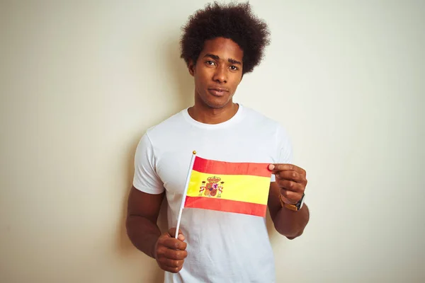 真剣に考えるスマートな顔に自信を持った表情で孤立した白い背景の上に立つスペインのスペインの旗を持つ若いアフロアメリカ人男性 — ストック写真