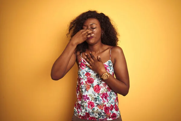 孤立した黄色の背景の上に花の夏のTシャツを着ているアフリカ系アメリカ人の女性は 鼻に指で息を保持し 臭いと嫌な 耐えぎにくい何かを臭い 悪臭の概念 — ストック写真