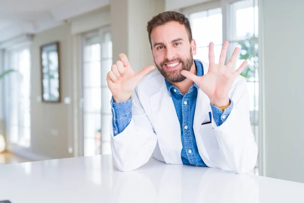 英俊的医生男子穿着医疗外套在诊所显示和指着手指六号 同时微笑自信和快乐 — 图库照片