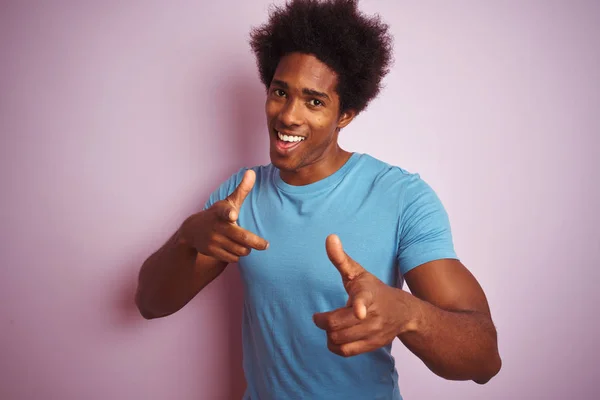 非洲裔美国男子 一个非洲头发 穿着蓝色T恤站在孤立的粉红色背景 指着镜头与快乐和有趣的脸 良好的能量和氛围 — 图库照片