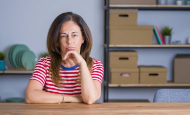 Orta yaş yaşlı kadın evde masada oturan yorgun görünümlü ve çapraz kolları ile depresyon sorunları ile sıkılmış düşünme.