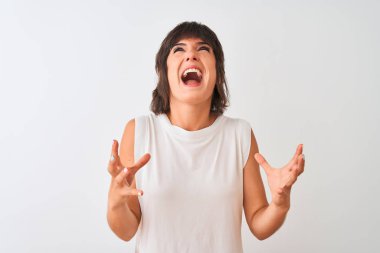 Genç güzel kadın izole beyaz arka plan üzerinde ayakta rahat t-shirt giyen çılgın ve deli bağırma ve agresif ifade ve kollar ile bağırdı kaldırdı. Hayal kırıklığı kavramı.